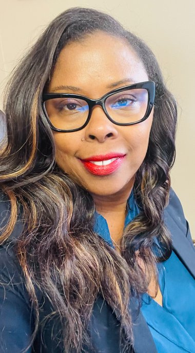 Portrait of Dr. Tracy Lynn: an African American woman wearing a navy blazer, blue top with long hair and red lipstick. She is smiling.